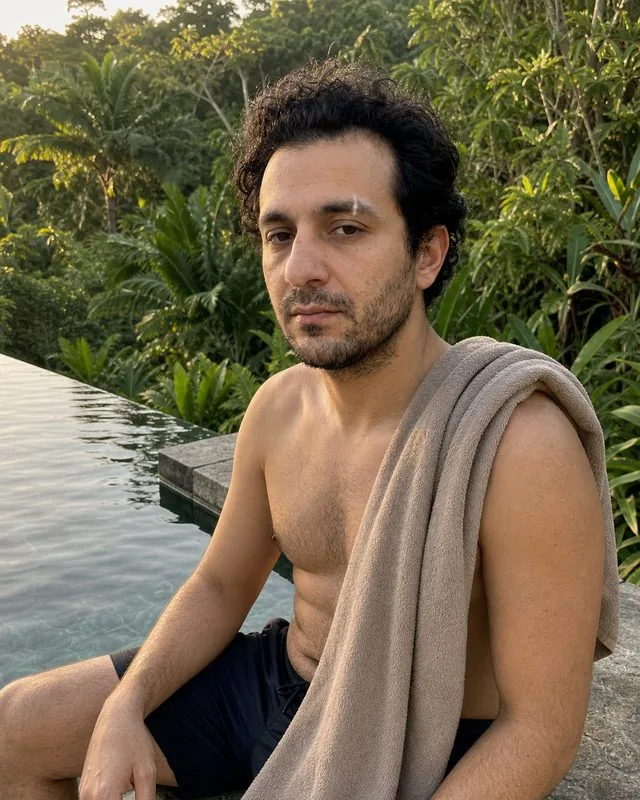 Bali: sitting at the edge of a stone infinity pool in swim shorts with a towel over one shoulder