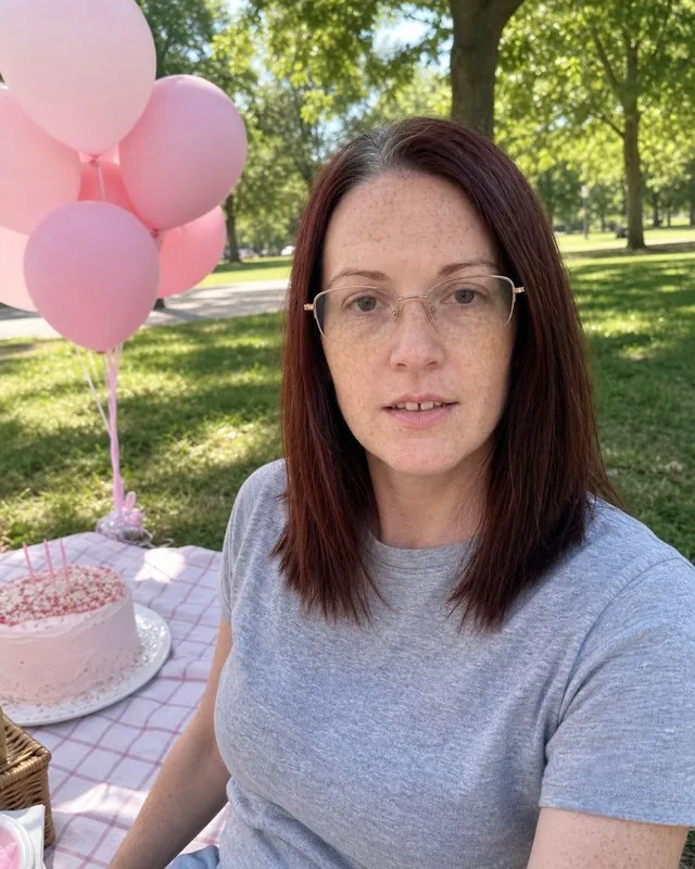Birthday picnic: at a park picnic with pink balloons and a cake on a blanket, bright summer light