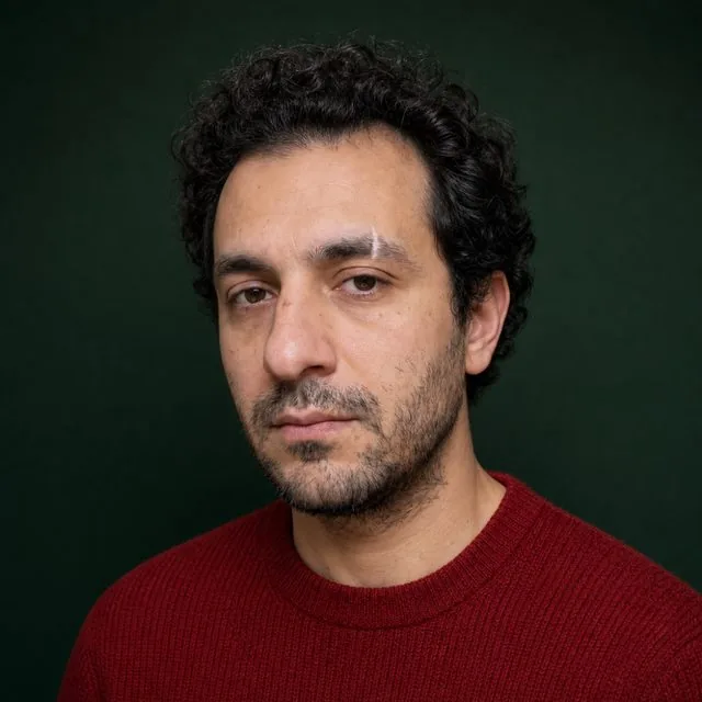 Christmas card: a posed festive portrait against a deep green backdrop with soft studio light, red knitwear