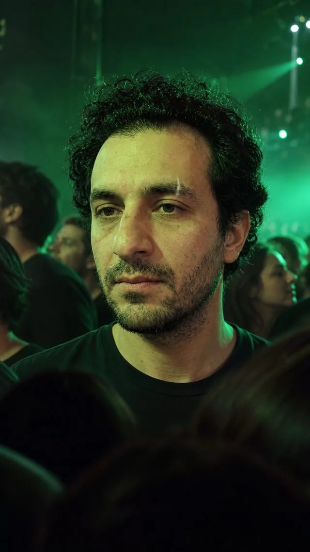 Concert: a candid frame lit by a green stage wash, silhouetted heads in the foreground