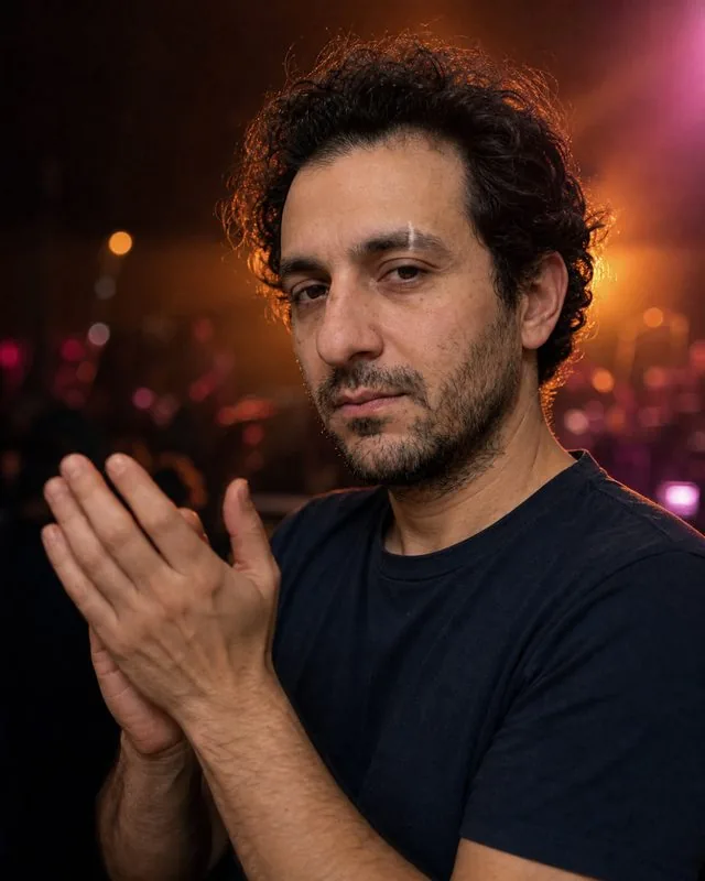 Live music: clapping between songs with the stage glow behind, shallow depth of field, grainy low light