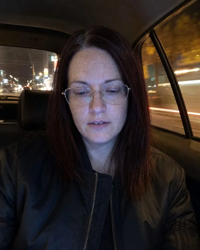 Night out: in the back of a taxi at night in a dark bomber jacket, street lights streaking past the window