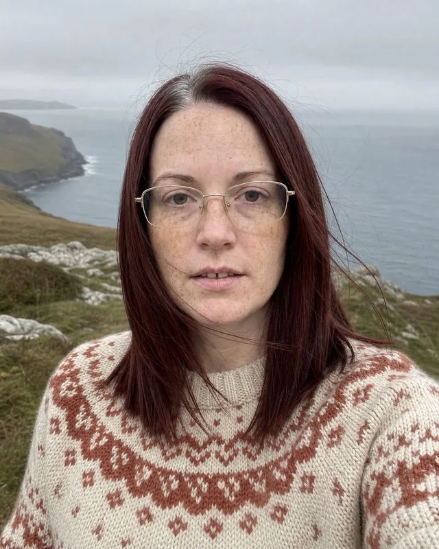 Heritage knit: a portrait in a hand-knitted fair-isle jumper in cream and rust, standing on a windswept headland
