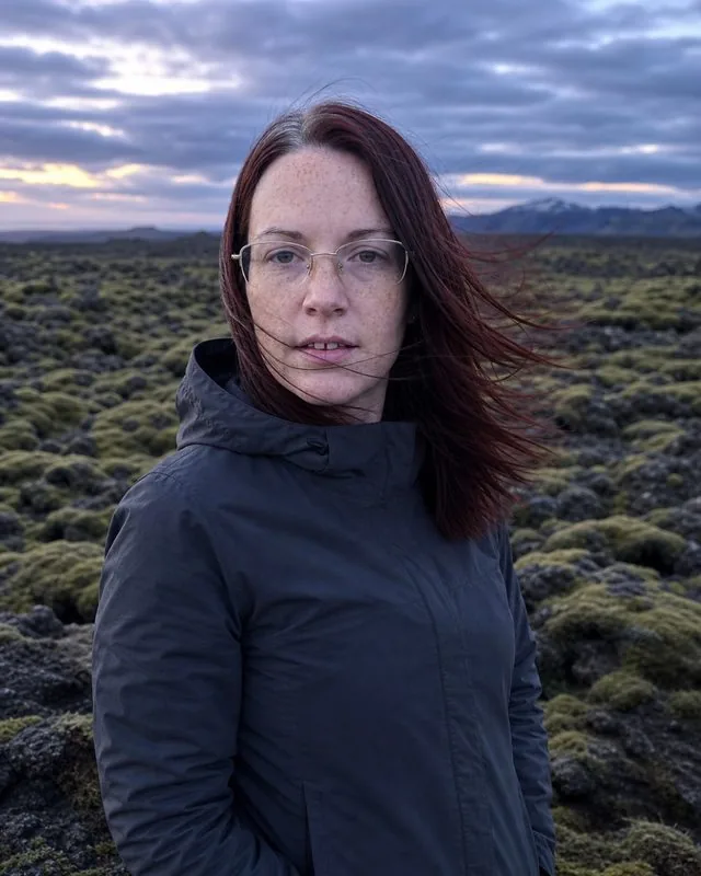 Iceland: on a moss-covered lava field at dusk, wind flattening the clothes, deep blue light