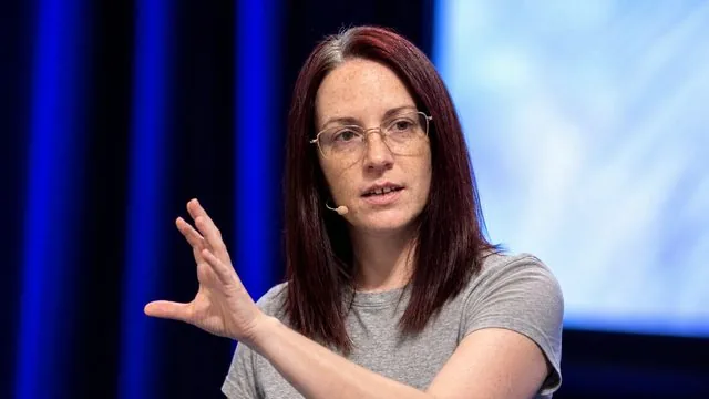 Keynote speaker: on a conference stage with a headset microphone, mid-gesture