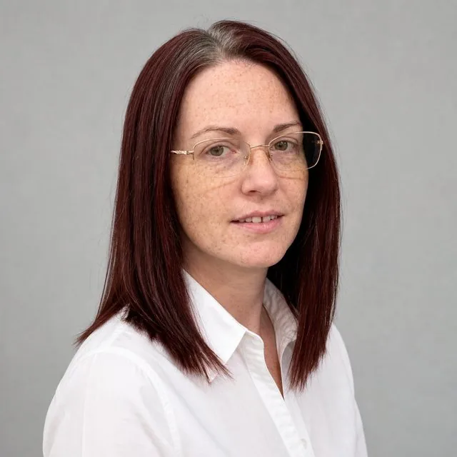 LinkedIn: a clean profile photo on a light grey seamless background, crisp white shirt, friendly closed-mouth smile