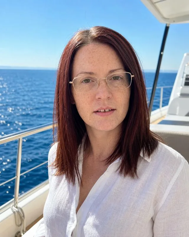 Luxury lifestyle: on a yacht deck in white linen, bright sea light and deep blue water behind