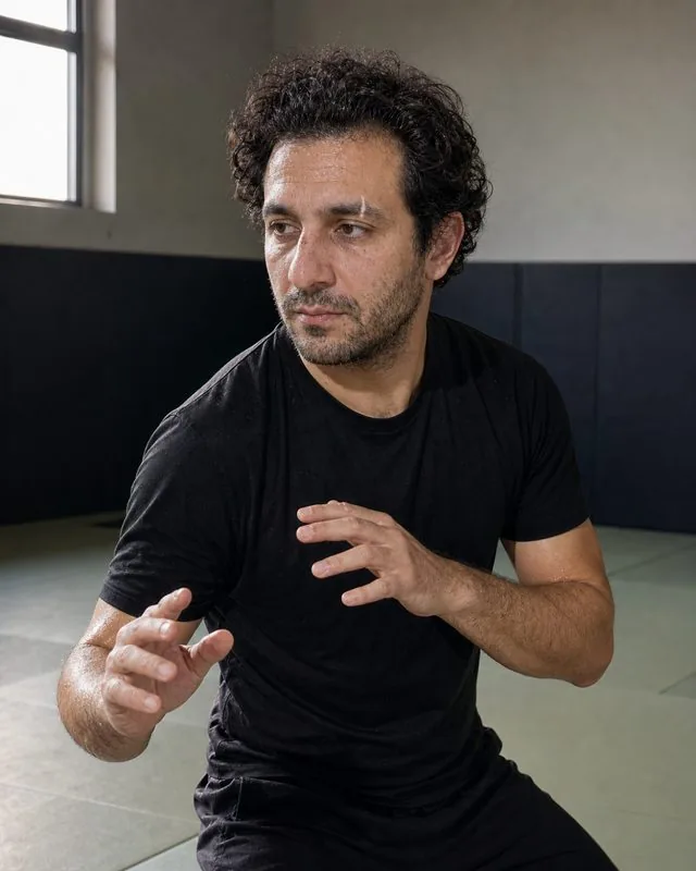 Martial arts: mid-stance in a training hall with hard side light, sweat and focused expression