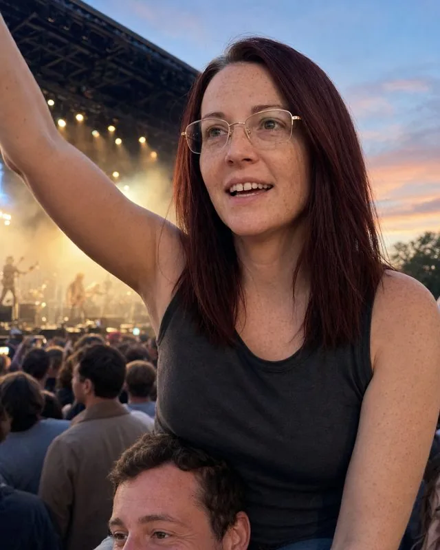 Festival: sitting on a friend’s shoulders at the front of a stage, warm dusk light and haze