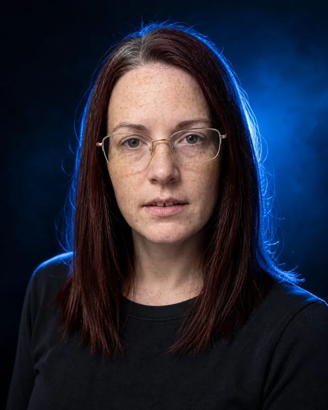 Neon studio: with light haze in the air and a hard blue backlight, plain dark clothing