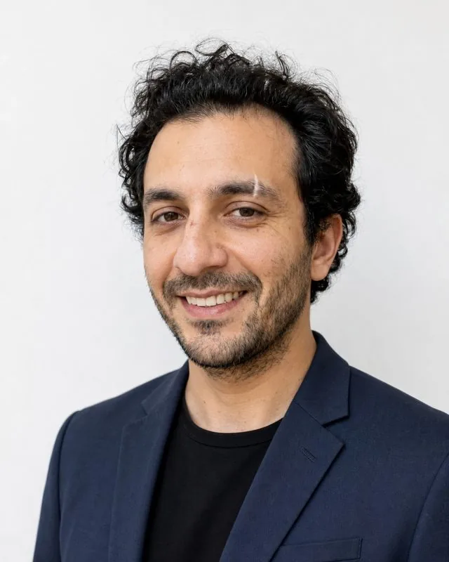 Real estate agent: a headshot against a clean white wall, sharp blazer, confident open smile
