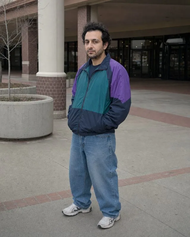 1990s: outside a shopping centre in a 90s windbreaker and baggy jeans, flat overcast light and faded colour