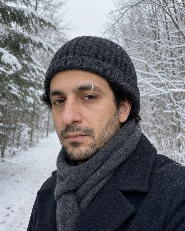 Snow: on a snowy forest path in a wool hat and scarf, snow-laden branches behind, flat cold light