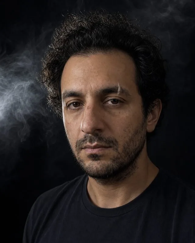 Smoke and shadow: a dark studio portrait with a single hard light and smoke drifting through the beam