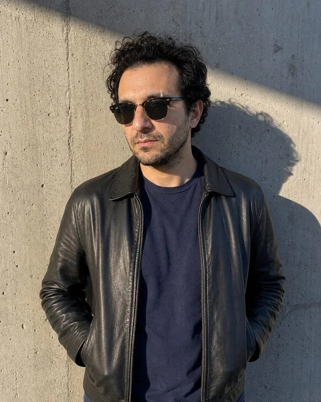 Street style: standing against a concrete wall with sunglasses on, boxy leather jacket, hands in pockets