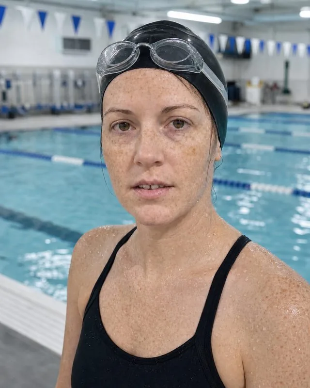 Swimming: at the edge of a 50m pool in a swim cap and goggles pushed up, wet skin