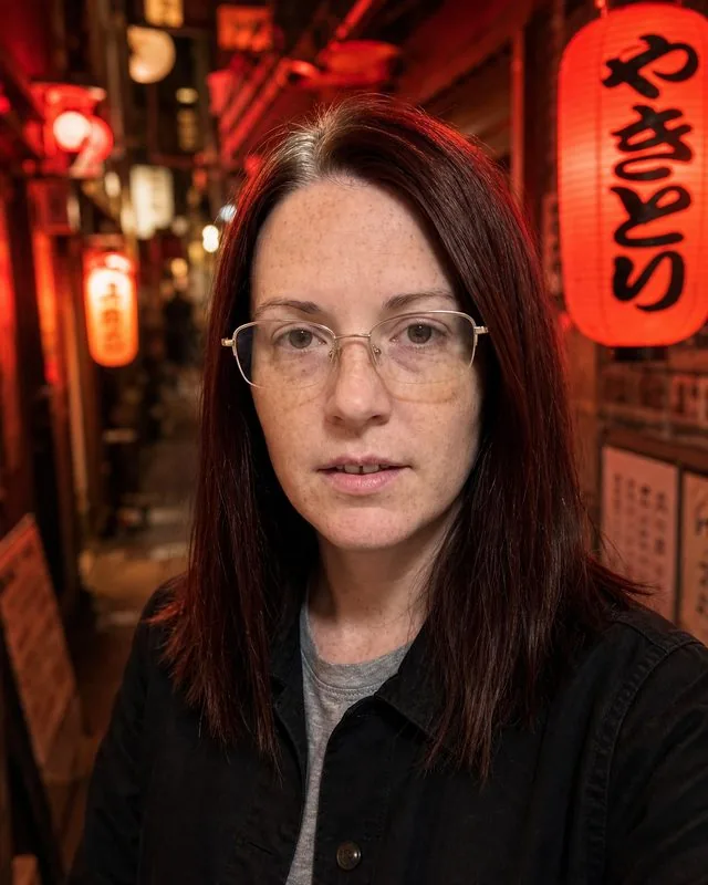 Tokyo night: in a narrow alley of small izakaya lanterns, black overshirt, warm red glow, shallow depth of field