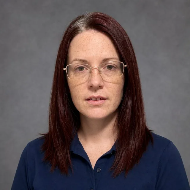 Yearbook: a class-photo style portrait against a plain grey backdrop, plain collared shirt